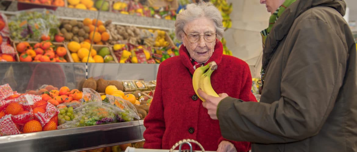 A young female caretaker and a senior woman grocery shopping together