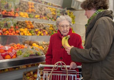 A young female caretaker and a senior woman grocery shopping together