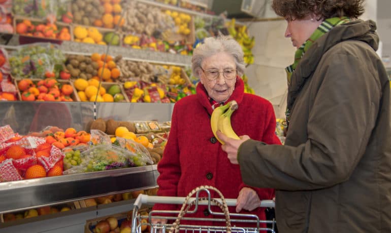 A young female caretaker and a senior woman grocery shopping together