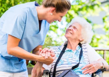 Nurse holding hand of senior woman in pension home