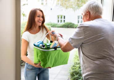 photo of female handing green basket to senior male