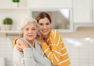 Senior female pictured hugging female caregiver or relative