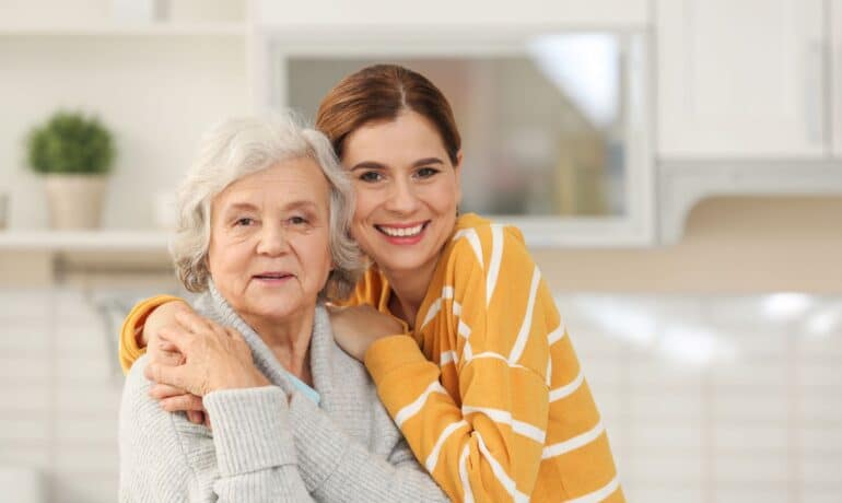 Senior female pictured hugging female caregiver or relative