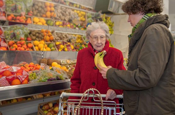 A young female caretaker and a senior woman grocery shopping together